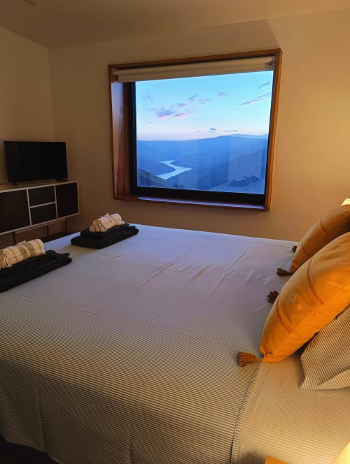 Quarto com vista para vale fluvial na Quinta do Fraguil, com cama, TV e paisagem montanhosa com vista para o rio