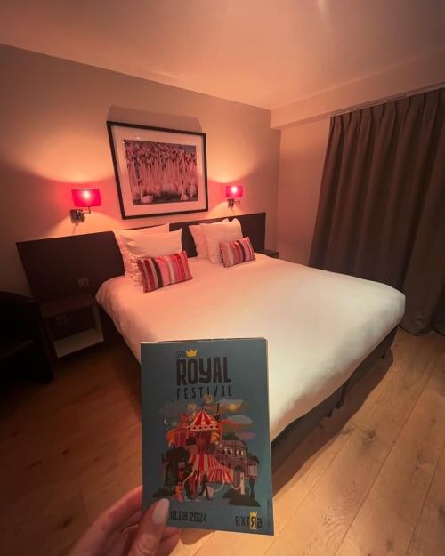 Chambre moderne de l'Hôtel Le 24 à Spa avec éclairage ambient rouge, lit blanc et brochure Royal Festival