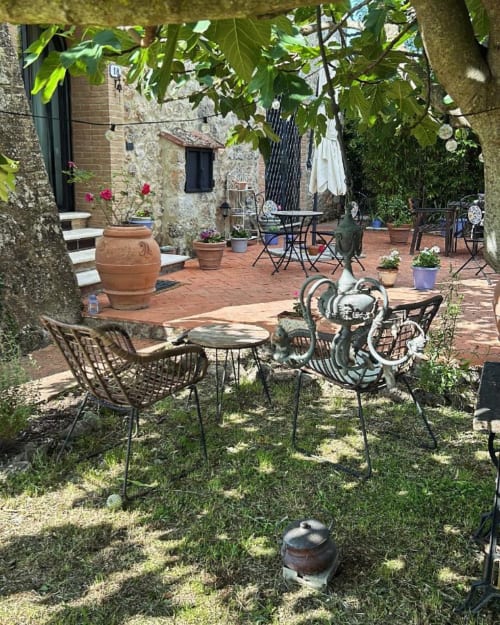 Sedute rustiche nel cortile di Torre Della Chiocciola B&B a Monteriggioni, Siena, con vasi in terracotta e vista sul giardino