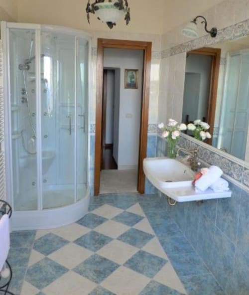 Bagno moderno della B&B Torre Della Chiocciola con doccia in vetro curvo, doppio lavabo, grande specchio e piastrelle blu-crema