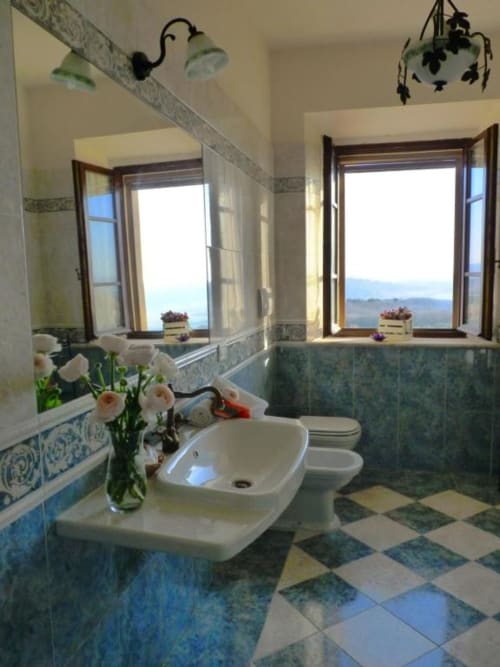 Luminoso bagno con doppi lavabi, fiori e finestre panoramiche sulla catena montuosa di Monteriggioni presso Torre Della Chiocciola