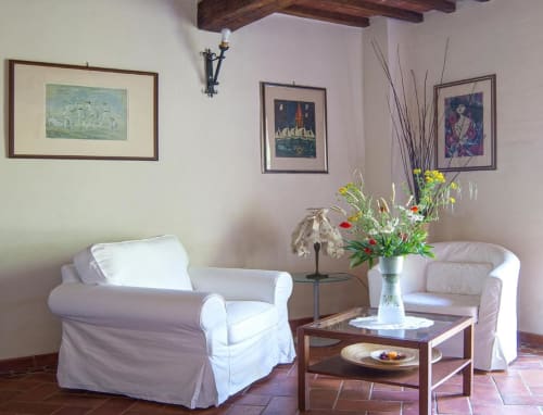 Elegante salotto a Torre Della Chiocciola Monteriggioni con poltroncine bianche, travi in legno, quadri incorniciati e freschezza