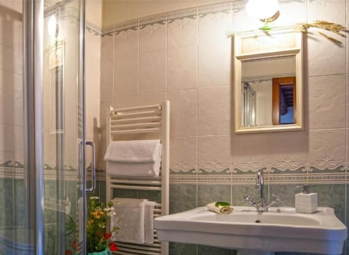 Elegante bagno nella Torre Della Chiocciola B&B, Monteriggioni, con scaldasalviette, lavabo su colonna, specchio incorniciato e