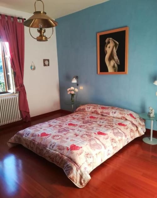 Camera da letto della Torre della Chiocciola con pareti turchesi, letto con coperta rossa a motivi, lampada a sospensione in ottone e opere d'arte incorniciate.
