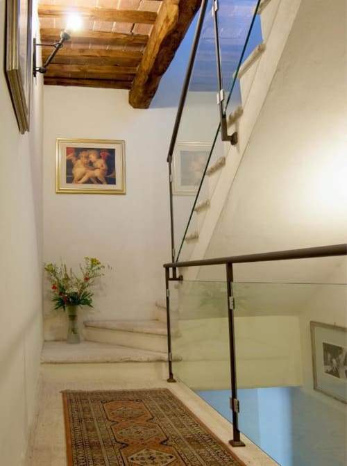 Scala moderna con ringhiera in vetro a Torre Della Chiocciola B&B, Monteriggioni. Travi a vista, opere d'arte e fiori freschi.