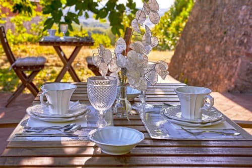 Elegante tavolo all'aperto alla Torre Della Chiocciola B&B a Monteriggioni, Siena, con stoviglie bianche e elementi sospesi