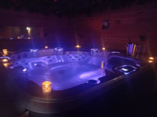 Baignoire à remous illuminée de la villa La Maison du Plaisir à Isigny sur Mer avec éclairage ambiant violet et jets d'eau