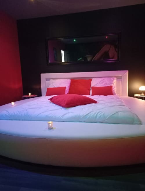 Lit rond moderne aux oreillers rouges dans la chambre luxueuse de La Maison du Plaisir à Isigny sur Mer