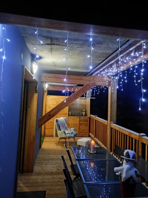 "Balcon de l'appartement à Vars-les-Claux vu de nuit, décoré de guirlandes lumineuses pour évoquer l'ambiance hivernale et chaleureuse, parfait pour profiter des soirées après une journée de ski."
