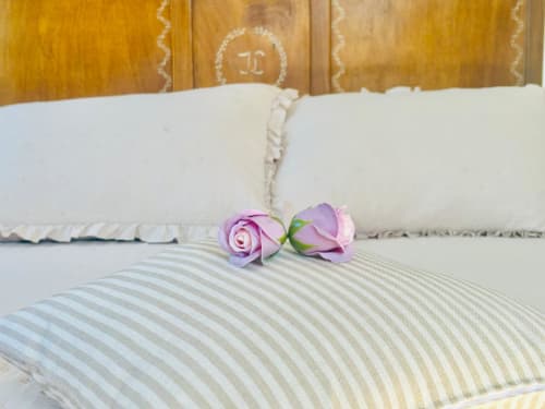 Cama elegantemente decorada con almohadas a rayas y rosas púrpuras en la casita Casa Caeiro de Baiona