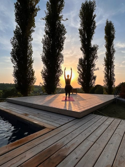 Woman doing yoga on wooden platform at sunset, Domaine de Blanvatel, Saint Pierre en Auge