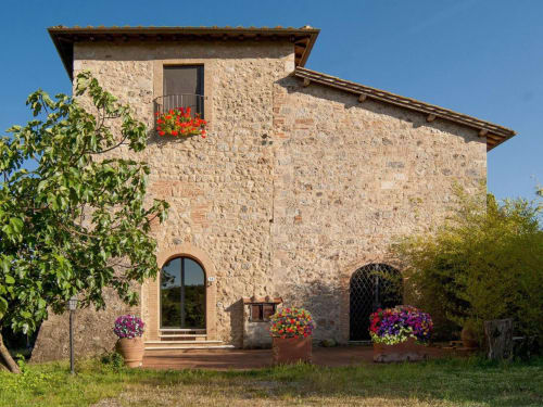Torre in pietra B&B con fiori rossi alla finestra, Monteriggioni, Siena, Italia