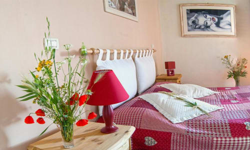 Camera accogliente al B&B Torre Della Chiocciola di Monteriggioni con biancheria rossa, fiori freschi e arredamento caldo
