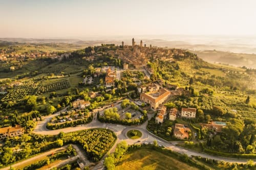 Vista aerea di Monteriggioni, borgo medievale senese in Toscana, circondato da colline verdi e vigneti al tramonto