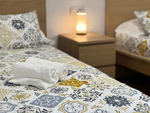 Chambre accueillante à Can Ricós avec serviettes roulées sur la literie à motifs, lampe de chevet et coussins décoratifs à Vallgorguina