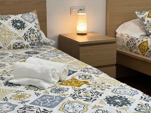 Chambre moderne à l'auberge rurale Can Ricós à Vallgorguina avec lits jumeaux, literie à motifs et lampe de chevet chaleureuse