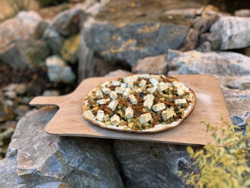 Gourmet pizza with vegetables and cheese on wooden board at Château Ségot, Neuilly-le-Réal