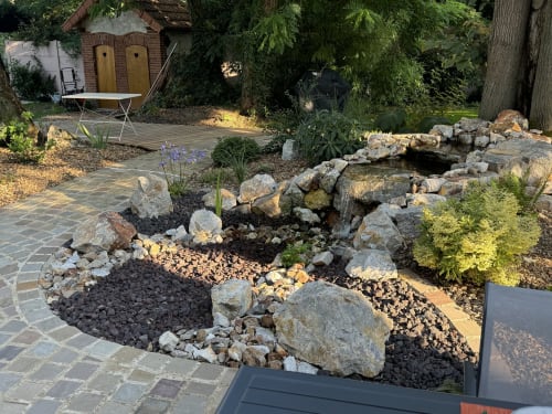 Château Ségot garden patio with stone pathways, decorative rock landscaping, and seating area in Neuilly-le-Réal, France.