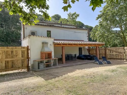 Auberge rurale Can Ricós à Vallgorguina, Barcelone : bâtiment blanchi à la chaux, terrasse et portails en bois entourés d'arbres