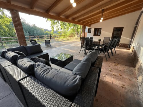 Patio couvert avec mobilier noir et zone de restauration au refuge rural Can Ricós à Vallgorguina, Barcelone
