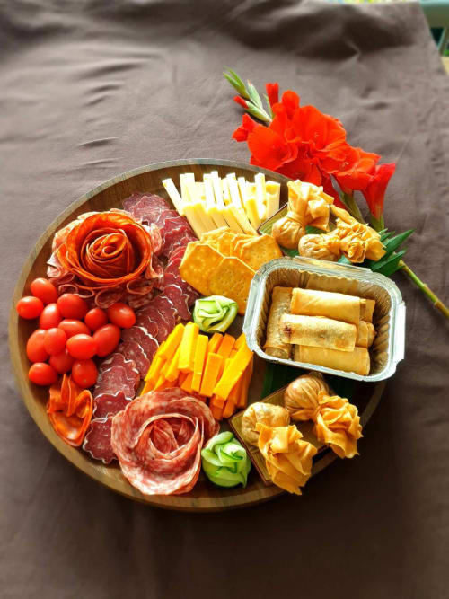 Plancha de charcuterie élégante avec charcuteries, fromages, crackers, légumes frais et fleurs chez Les Secrets de Winna romantique