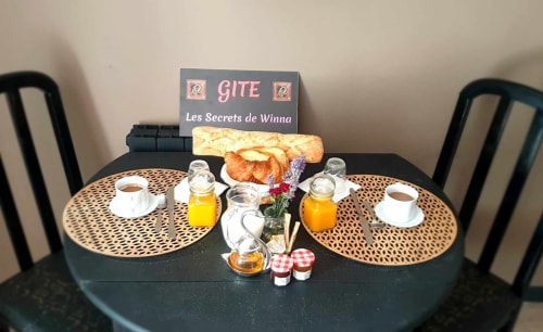 Petit-déjeuner romantique aux Secrets de Winna avec croissants, jus, café et fleurs sur table noire