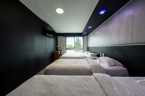 Moderna habitació familiar per a 5 persones a l'Hôtel Rocade de Pamiers amb tres llits, vistes al jardí i accents contemporanis foscos