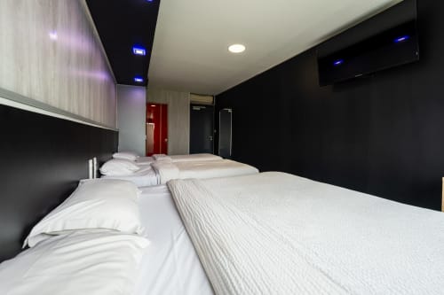Ampla habitació familiar per a 5 persones a l'Hôtel Rocade Pamiers amb múltiples lits, TV de pantalla plana i decoració contemporània en blanc i negre