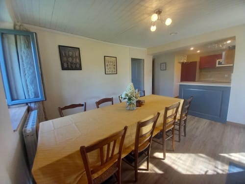 Spacieuse salle à manger de la villa La Maison De Fleurat avec table en bois, chaises, cuisine moderne et vue sur le jardin à Domeyrot