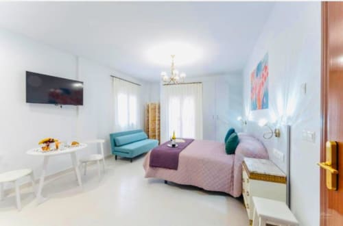 Moderno apartamento estudio en Mérida con sofá turquesa, cama rosa y vistas a la ciudad