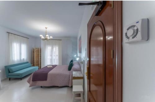 Dormitorio moderno con sofá turquesa, armario de madera y aire acondicionado en apartamento de Mérida