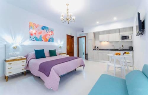 Moderno apartamento estudio en Mérida con ropa de cama rosa, cocina y arte colorido