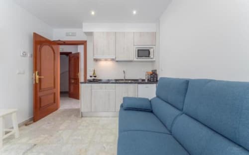 Apartamento moderno en Mérida con sofá azul, cocina americana y puerta de entrada de madera