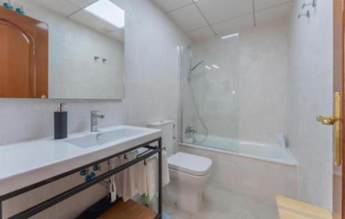 Cuarto de baño moderno con lavamanos, inodoro y ducha-bañera combinada en apartamento de Mérida