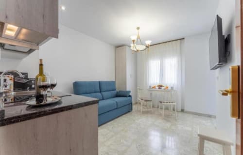 Apartamento moderno en Mérida con sofá azul, cocina, comedor y televisor de pantalla plana