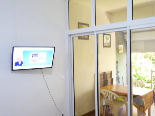 Intérieur de l'appartement Marina avec télévision murale et portes coulissantes vitrées ouvrant sur la salle à manger