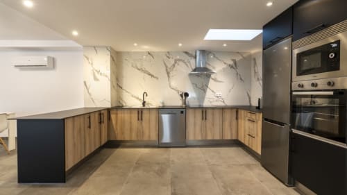 Moderna cocina en apartamento de Burriana con backsplash de mármol, muebles de madera, electrodomésticos de acero inoxidable e isla.