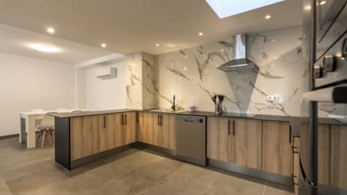 Cocina moderna en Apartamentos Burriana con muebles de madera, acabado de mármol y electrodomésticos de acero inoxidable