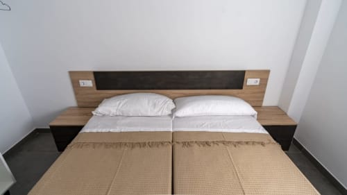 Dormitorio moderno en Apartamentos Burriana con cabecero de madera, almohadas blancas y ropa de cama beige en Burriana, España
