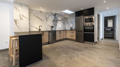 Cocina moderna en Apartamentos Burriana con backsplash de mármol, gabinetes negros, electrodomésticos de acero inoxidable e isla