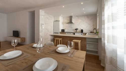 Comedor y cocina de planta abierta moderna en Apartamentos Burriana, con mesa de madera, salpicadero de mármol y accesorios contemporáneos