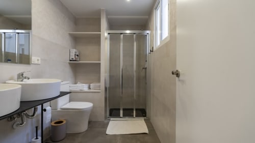 Baño moderno en apartamento Burriana con lavamanos redondo, inodoro y cabina de ducha