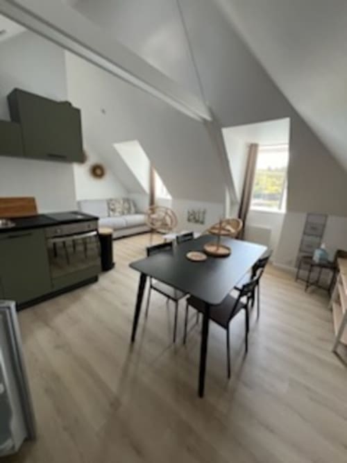 Appartement mansardé moderne à Locmaria avec table à manger, cuisine, coin salon et baies vitrées surplombant Belle Île en Mer