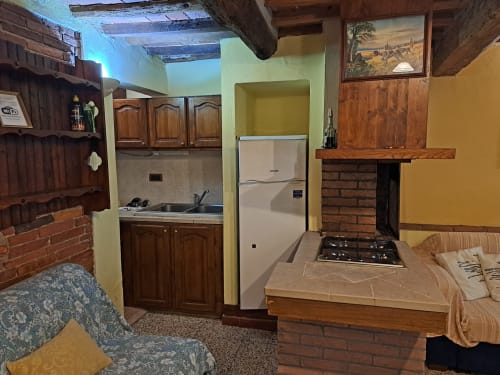 Cucina rustica e zona living della villa Corte Pincione a Montecarlo, con travi in legno, camino in mattoni e arredamento tradizionale