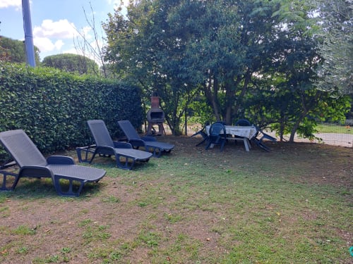 Terrazza esterna della villa Corte Pincione a Montecarlo con lettini, tavolo da pranzo e lussureggianti alberi da giardino
