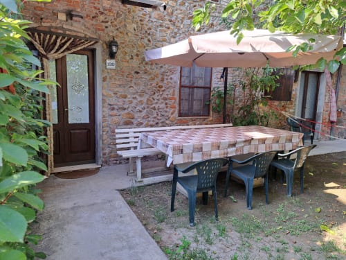 Corte della villa Pincione a Montecarlo con muri in laterizio, tavolo da pranzo, ombrelloni e edera verde