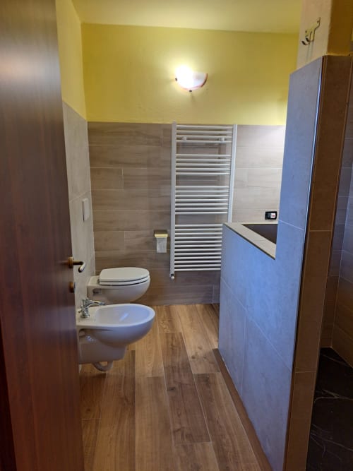 Bagno moderno nella villa Corte Pincione, Montecarlo con bidet, WC, scaldasalviette e pavimento in legno
