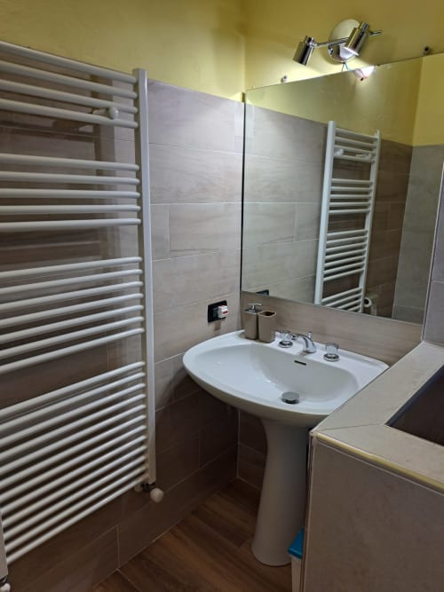 Bagno moderno della villa Corte Pincione a Montecarlo con lavabo su piedistallo, scaldasalviette e zona doccia piastrellata