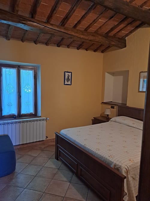Camera rustica con travi in legno, pavimenti in terracotta e arredi tradizionali alla villa Corte Pincione
