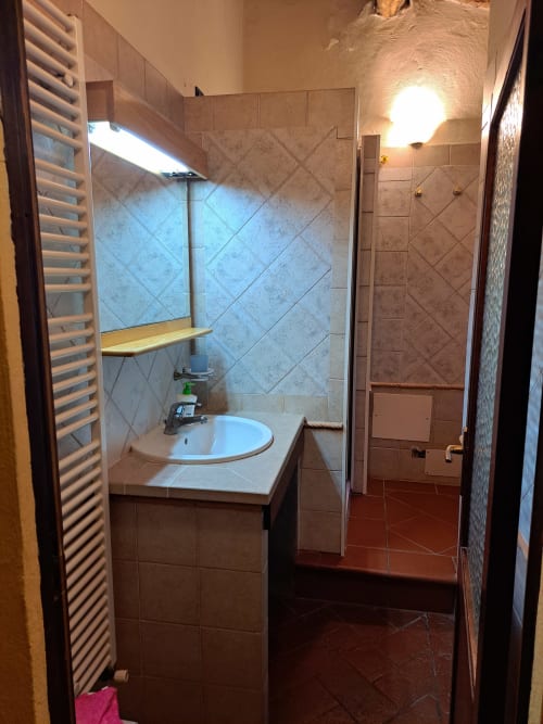 Bagno della villa Corte Pincione a Montecarlo con lavandino, doccia e pareti piastrellate